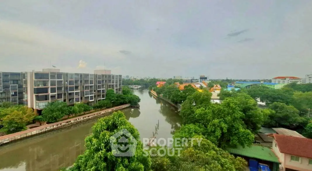 Scenic river view from a high-rise apartment, lush greenery and modern buildings.