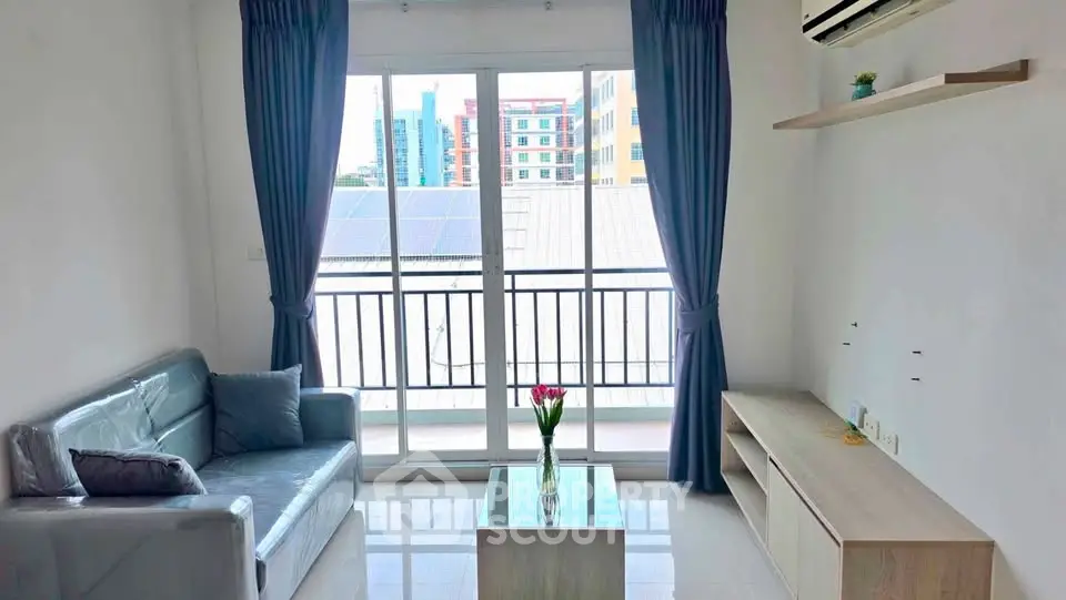 Bright living room with balcony view, modern sofa, and sleek furniture in urban apartment.