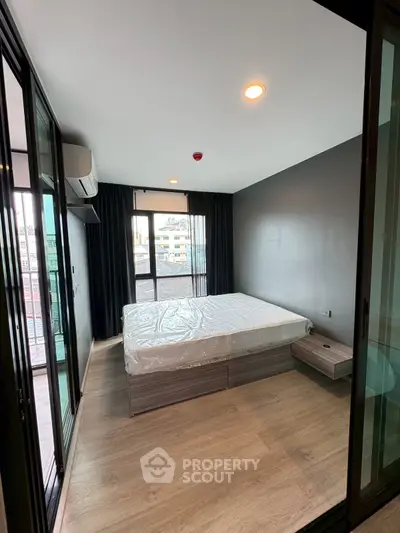 Modern bedroom with large windows and balcony access in urban apartment