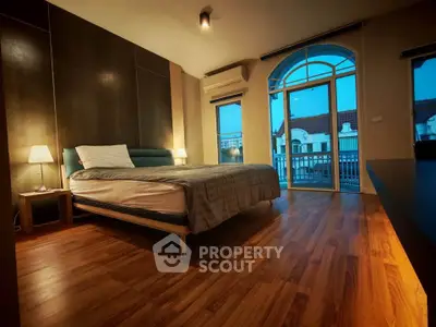 Spacious bedroom with elegant wooden flooring and balcony access