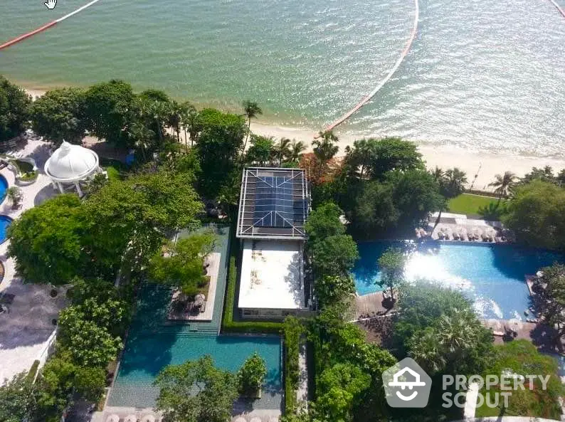 Stunning aerial view of beachfront property with lush gardens and luxurious pool area.