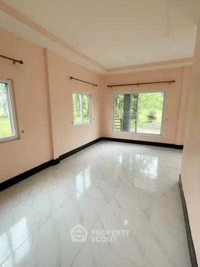 Spacious empty room with large windows and marble flooring, offering a serene garden view.