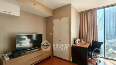Modern living room with TV, desk, and city view from large window.