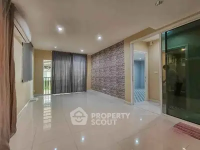 Spacious modern living room with large windows and stylish brick accent wall.