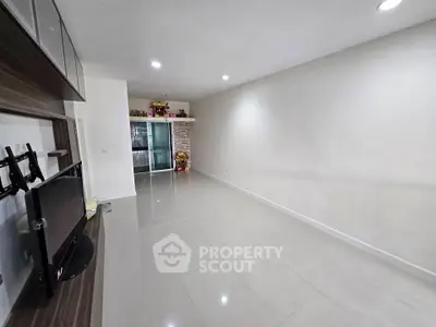 Spacious modern living room with sleek tile flooring and mounted TV, perfect for contemporary living.