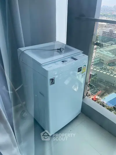 Modern washing machine on high-rise balcony with city view