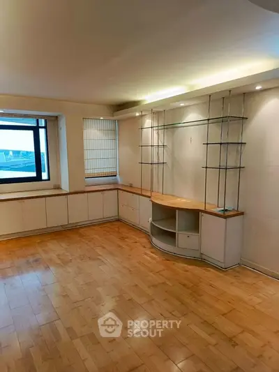 Spacious living room with wooden flooring and built-in shelves, perfect for modern living.