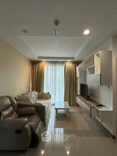 Modern living room with sleek furniture and large window offering natural light.