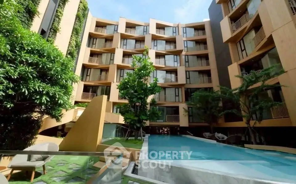 Modern apartment building with lush greenery and inviting pool area.