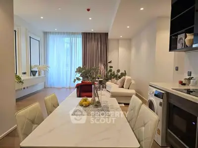 Modern open-plan living room with dining area and washing machine, featuring elegant decor and natural light.