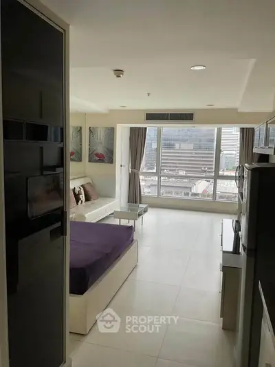 Modern living room with city view, featuring sleek furniture and large windows for natural light.