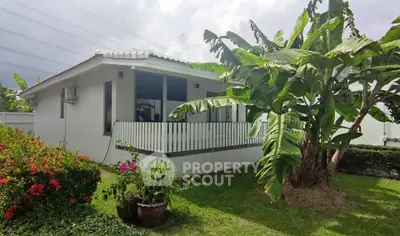 Charming white house with lush garden and banana trees, perfect for serene living.