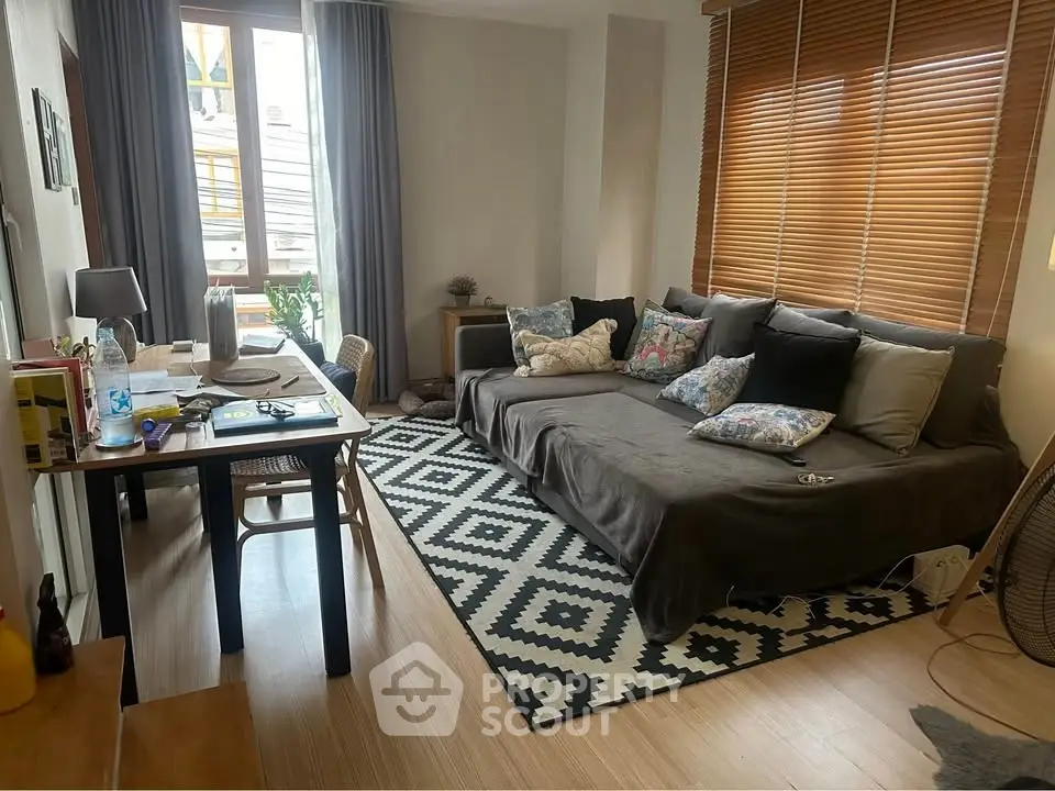 Cozy living room with stylish decor and natural light, featuring a comfortable sofa and a chic workspace.