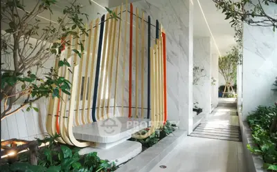 Luxurious modern building entrance with artistic bench and lush greenery