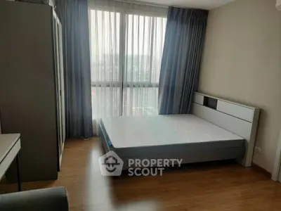 Modern bedroom with large window and minimalist furniture in a high-rise apartment.