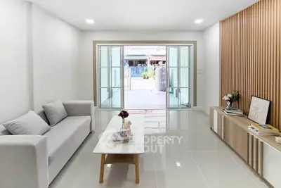 Modern living room with sleek design and large glass doors opening to outdoor space.