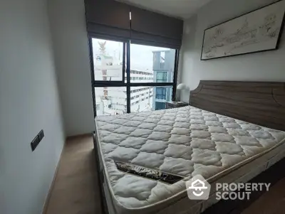 Modern bedroom with large window and city view, featuring a comfortable bed and stylish decor.