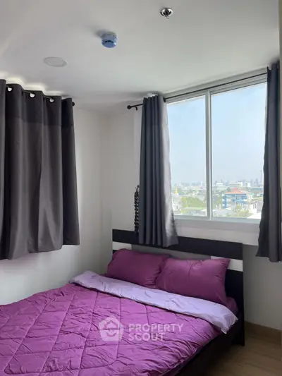 Cozy bedroom with purple bedding and city view from window