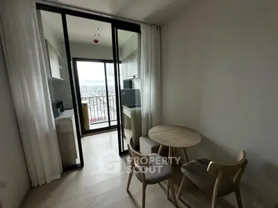 Modern apartment with open kitchen and balcony view, featuring sleek furniture and natural light.
