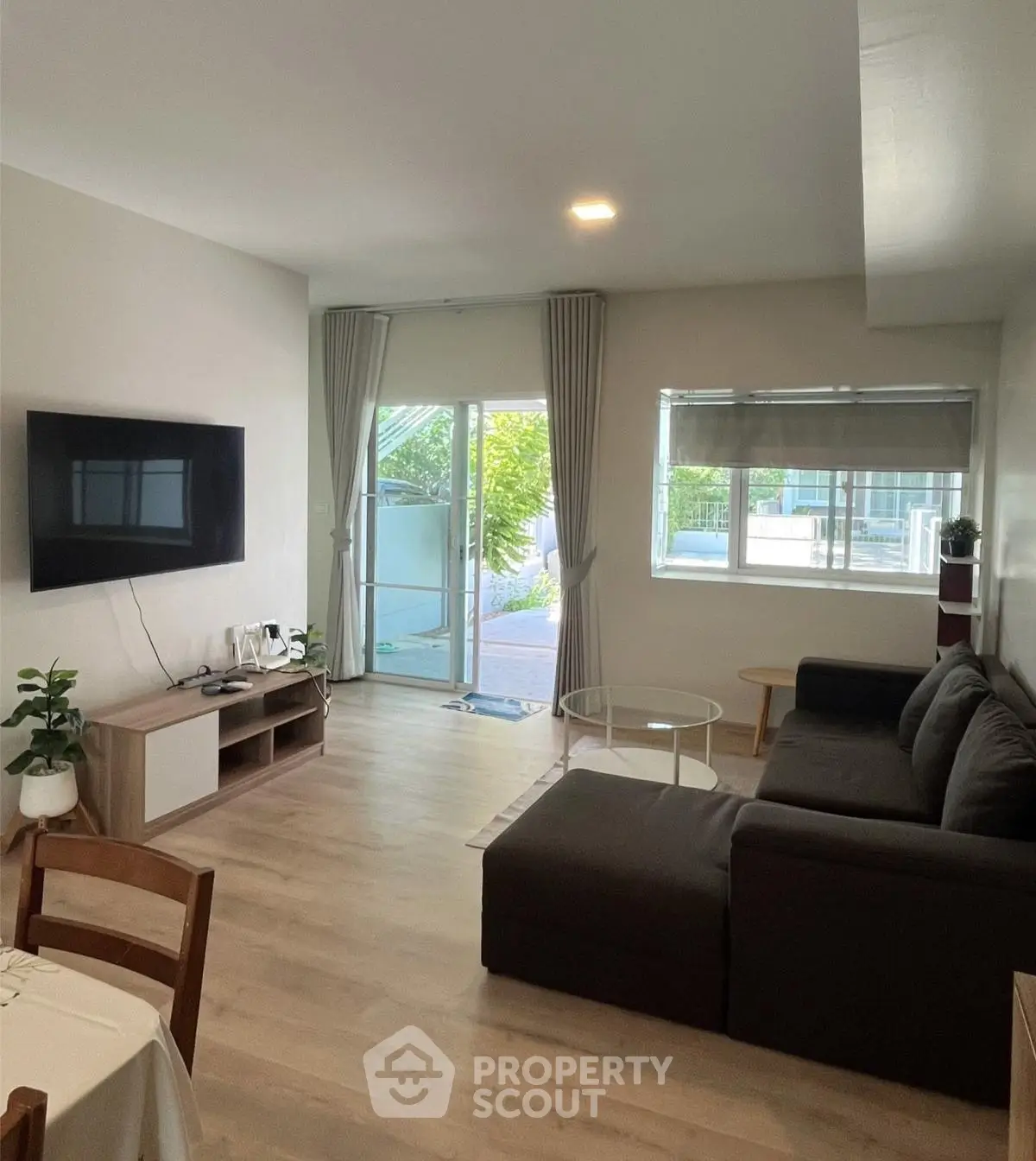 Modern living room with sleek furniture and large windows offering natural light and garden view.