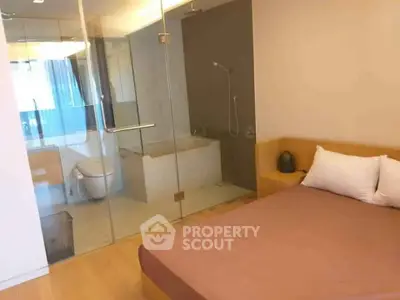 Modern bedroom with glass-enclosed bathroom featuring a bathtub and shower.