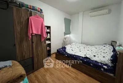 Cozy bedroom with wooden flooring and air conditioning, featuring a wardrobe and a fan for comfort.