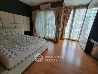 Spacious bedroom with elegant design, large windows, and wooden flooring for a cozy ambiance.