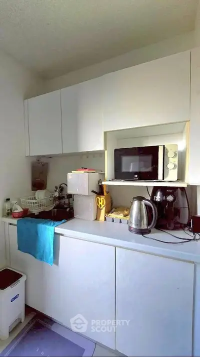 Compact kitchen with modern appliances and white cabinetry