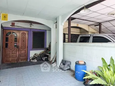 Charming home entrance with covered parking and lush greenery, perfect for family living.