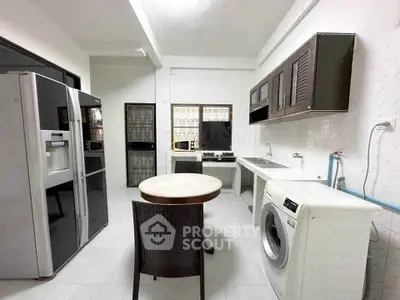 Spacious kitchen with modern appliances and washing machine in a bright, open layout.