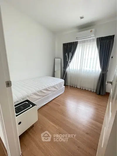 Cozy minimalist bedroom with wooden flooring and natural light