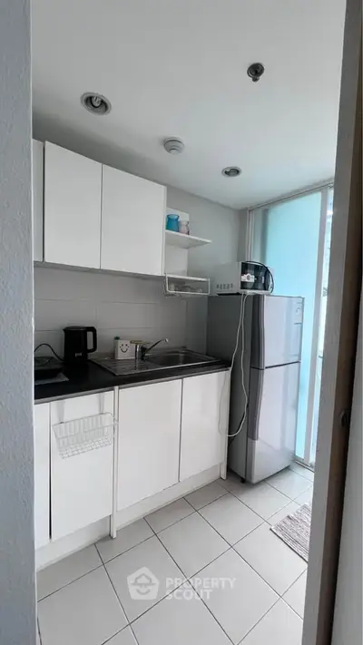 Modern compact kitchen with white cabinets and stainless steel appliances