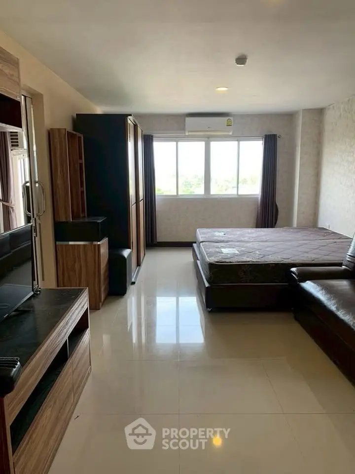 Spacious bedroom with modern furnishings and large window offering natural light.