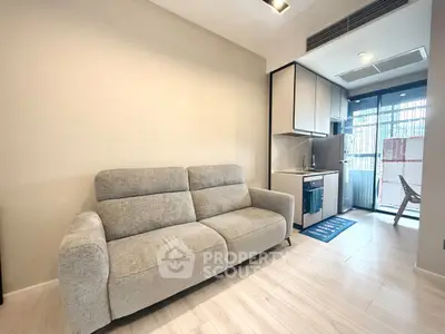 Modern living room with cozy sofa and compact kitchen in open layout apartment.