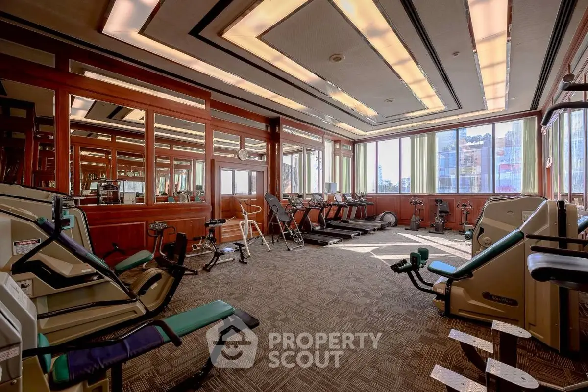 Spacious gym with modern equipment and large windows offering city views.