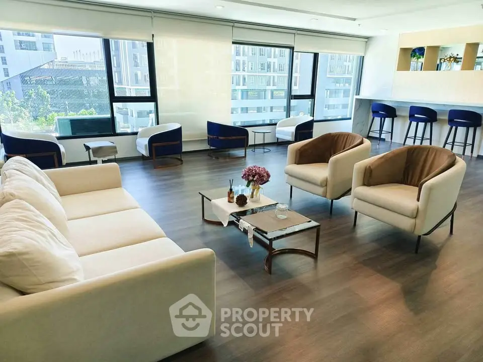 Spacious modern living room with large windows and stylish furniture in a high-rise apartment.