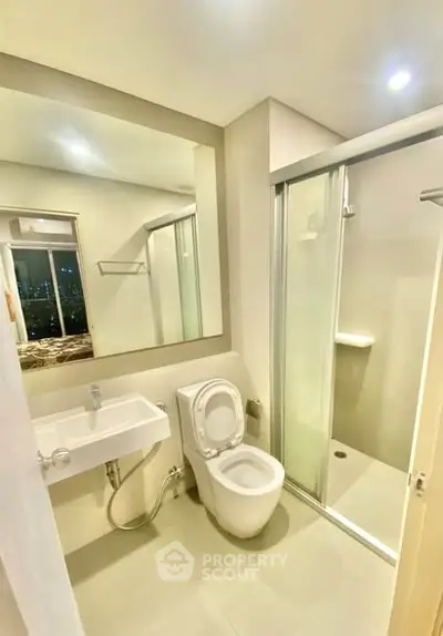Modern bathroom with sleek design and glass shower enclosure in a contemporary apartment.