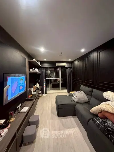 Modern living room with sleek black walls, cozy sectional sofa, and entertainment setup, perfect for relaxation.