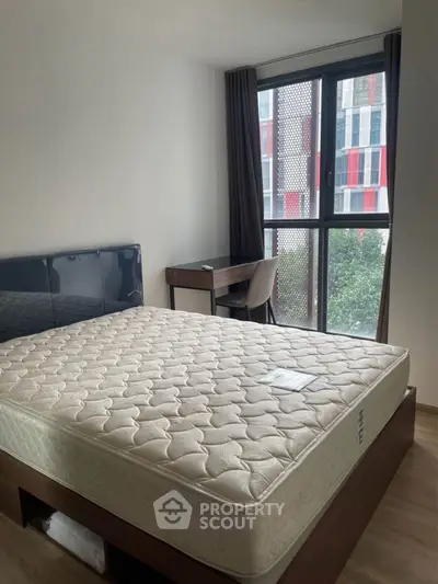 Modern bedroom with large window and natural light, featuring a comfortable bed and study desk.