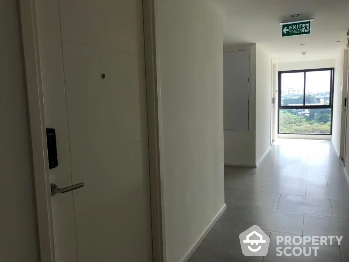 Modern apartment hallway with exit sign and window view