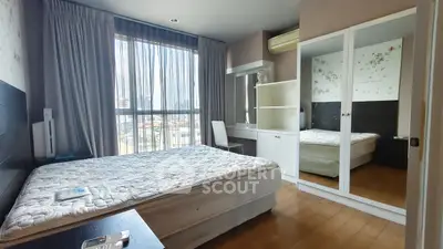 Spacious bedroom with large window and mirrored wardrobe in modern apartment.