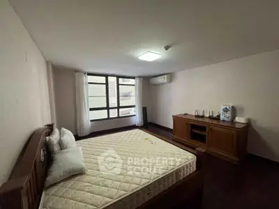 Spacious bedroom with large window and wooden furniture in modern apartment