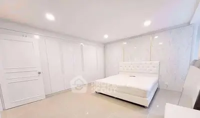 Spacious modern bedroom with elegant white decor and ample closet space.