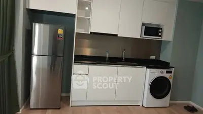 Modern kitchen with sleek appliances including fridge, microwave, and washing machine in a compact layout.