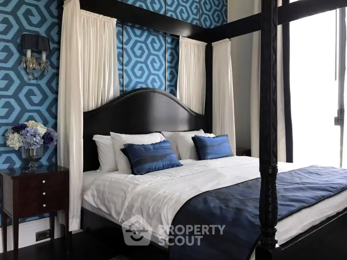 Luxurious bedroom with elegant four-poster bed and stylish geometric wallpaper.