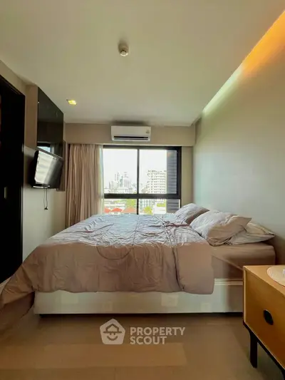 Cozy bedroom with city view, featuring modern decor and ample natural light.