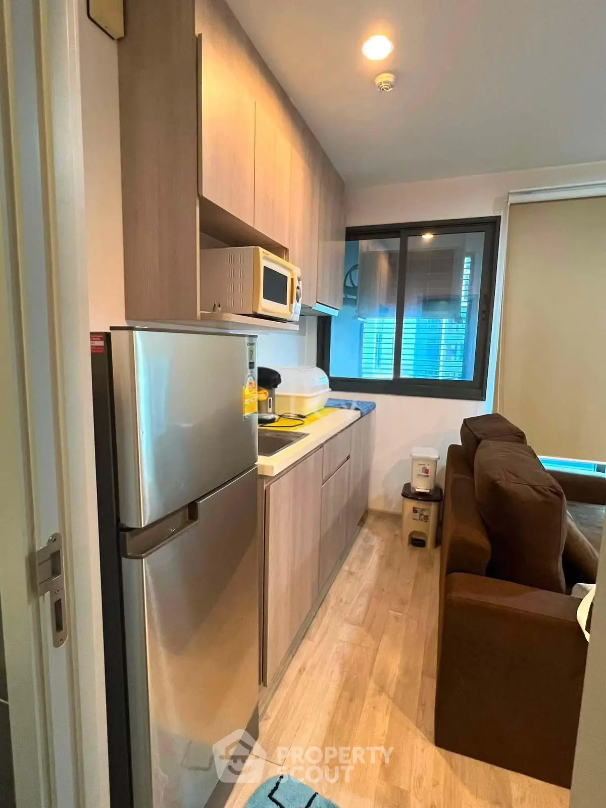 Modern compact kitchen with sleek appliances and cozy living area in stylish apartment.