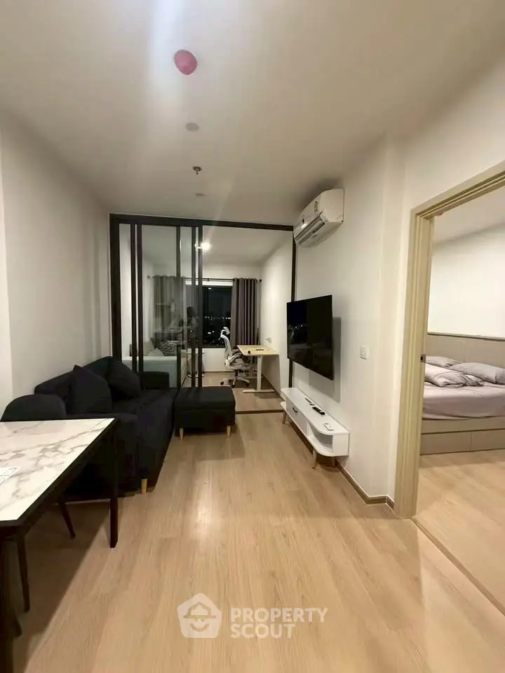 Modern living room with sleek furniture and open layout, featuring a cozy bedroom view.