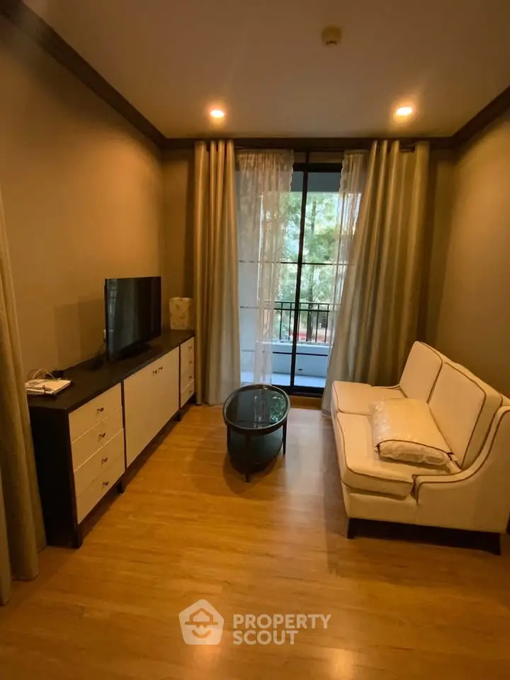 Cozy living room with elegant sofa, TV, and balcony view, perfect for relaxation and entertainment.