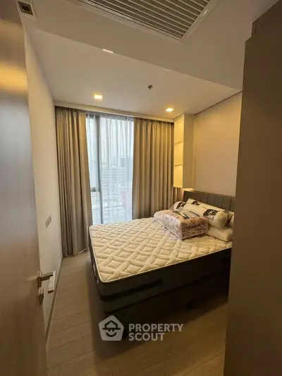 Cozy bedroom with modern decor and large window offering natural light